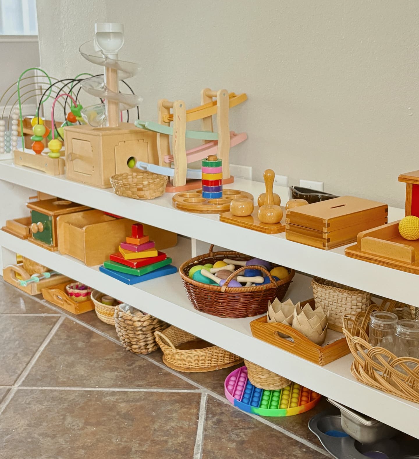 A toddler washing hands at a child-height wooden station